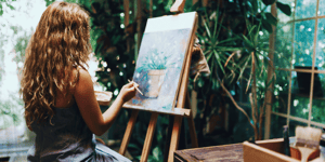 womam sitting at easel painting plant