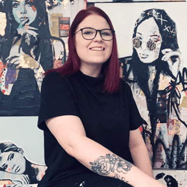 Mentor Tanya-Aubut sits in front of portrait paintings